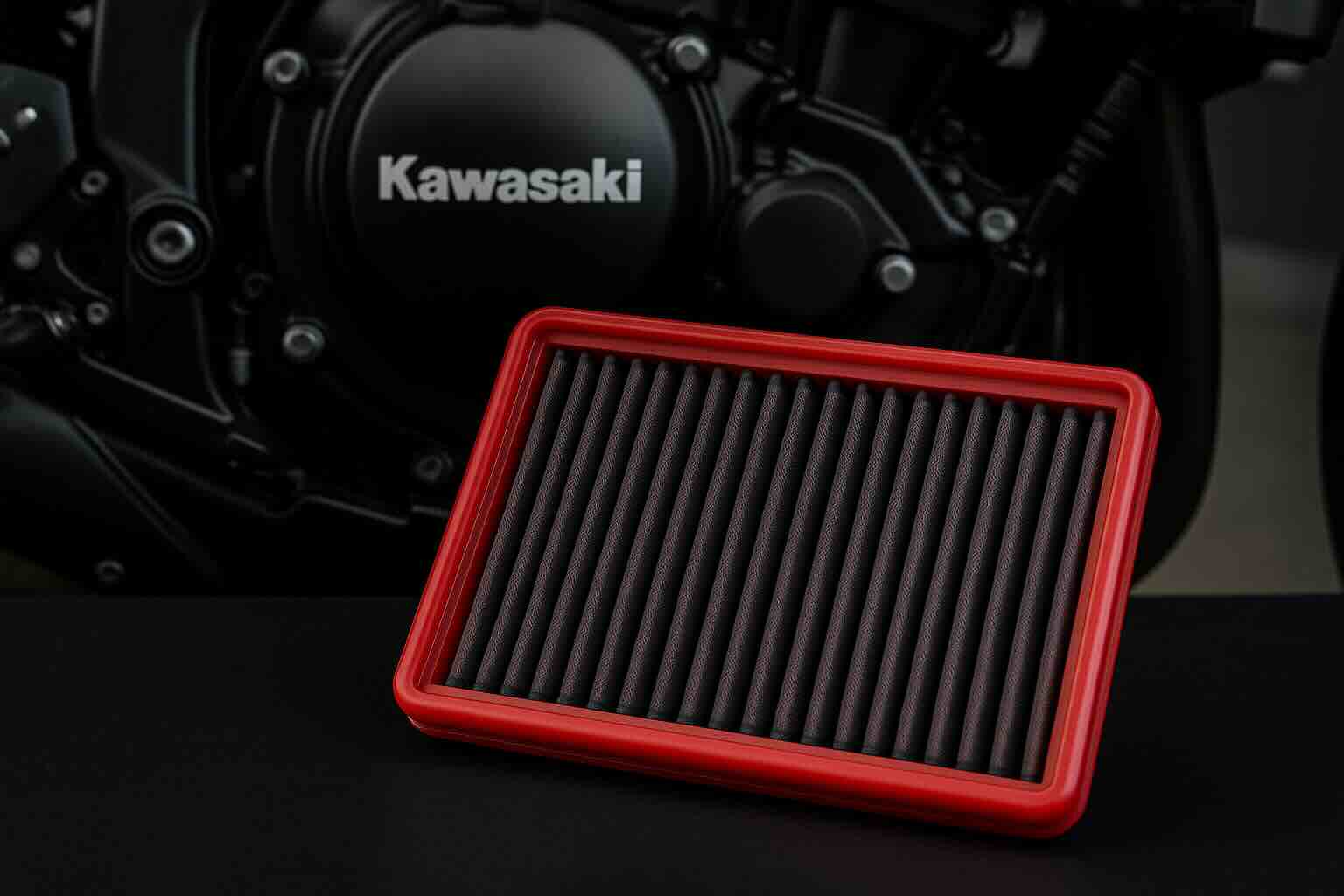 Red BMC performance air filter in front of a Kawasaki motorcycle engine – washable, high-flow filter designed for sportbike performance.
