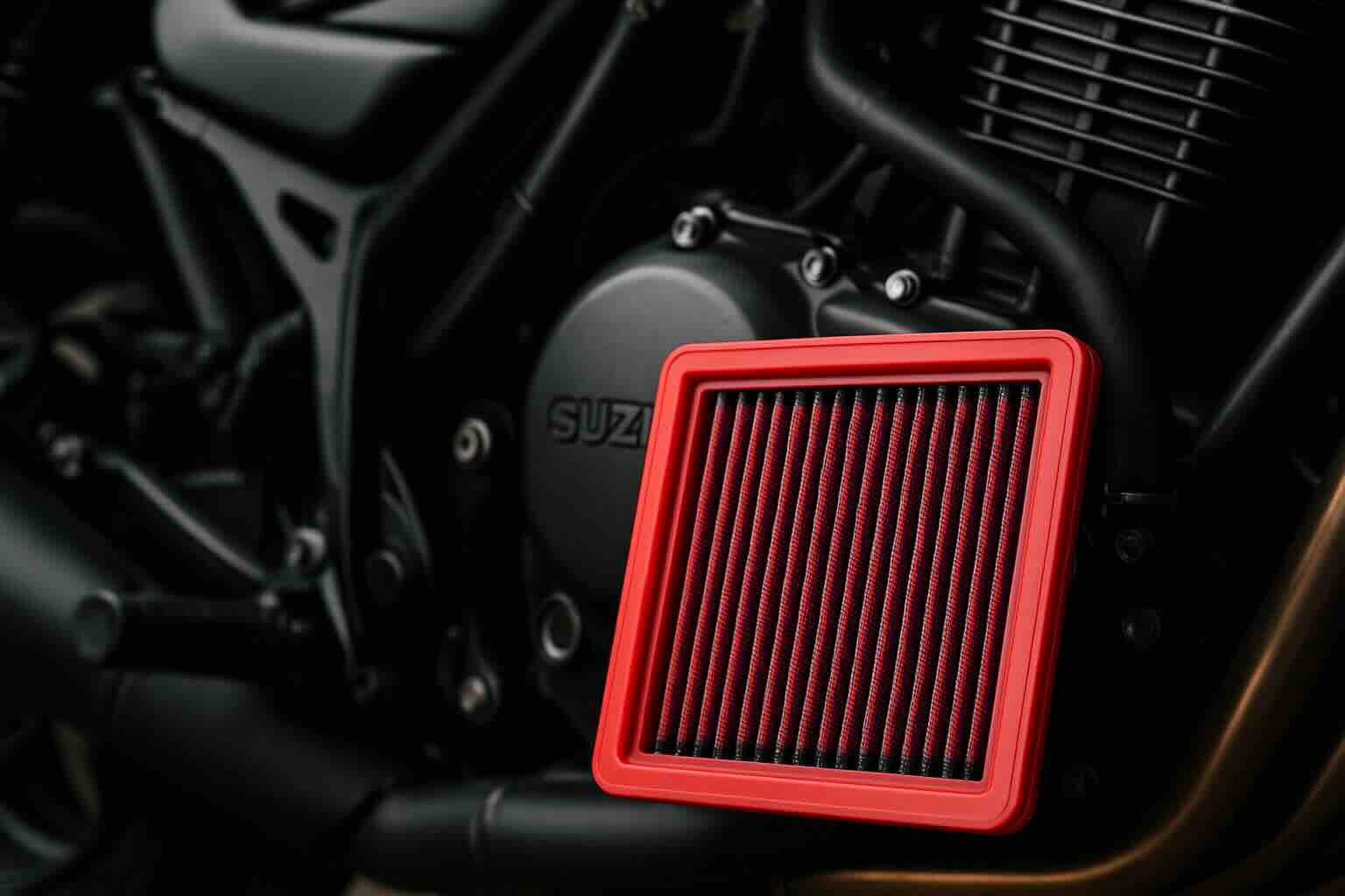 Red BMC performance air filter in front of a Suzuki motorcycle engine – washable, high-flow filter designed for sportbike performance and protection.