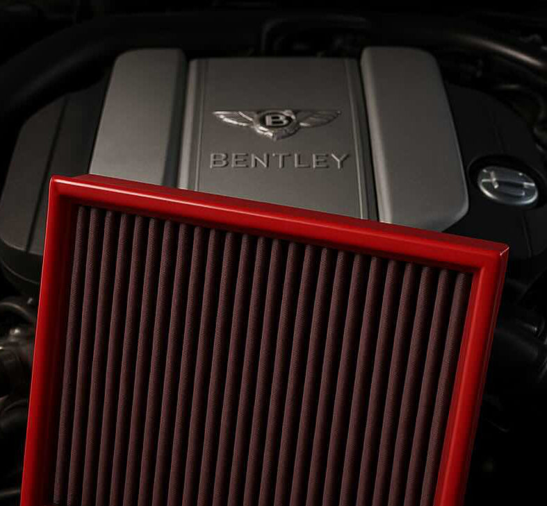 Red BMC performance air filter in front of a Bentley engine bay – premium washable filter for luxury performance cars.